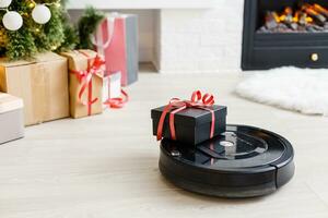 Robotic vacuum cleaner on laminate wood floor smart cleaning technology. Cristmas tree photo