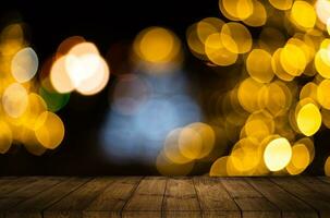 Old weathered wooden board or rustic table top with a sparkling bokeh of golden party lights in the background photo