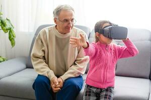 Granddaughter using virtual reality headset with her grandparents in living room at home photo