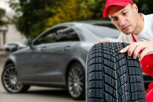 Mechanic holding a tire tire at the repair garage. replacement of winter and summer tires. photo