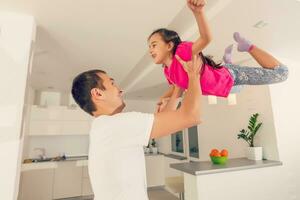 Happy family. Young father playing silly with his daughter lifting her up photo