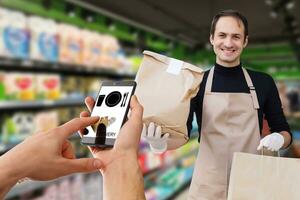 delivery food service at home. Man courier delivered the order no name bag with food. Hand holding smart phone with food online device on screen photo