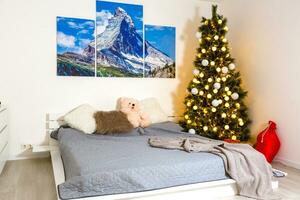 Wrapped presents on a bed near decorated Christmas tree in hotel room in the morning photo