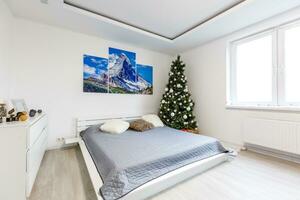 Calm image of interior Classic New Year Tree decorated in a room with bed photo