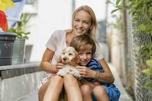 Portrait of mother snd son cuddling with cute dog puppy photo
