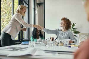 Happy businesswomen having a meeting and shaking hands in office photo