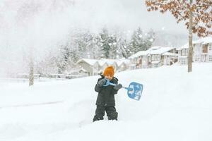 Laughing little boy shoveling snow, Vancouver, Canada photo