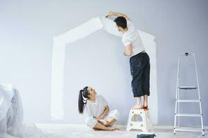 Couple painting house shape on wall in new apartment photo