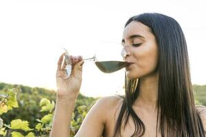 Italia, toscana, siena, joven mujer Bebiendo rojo vino en un viñedo a puesta de sol foto