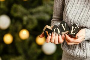 mujer sostiene letras amor cerca Navidad árbol con juguetes foto