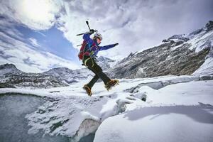 Female mountaineer jumping over crevasse, Glacier Grossvendediger, Tyrol, Austria photo