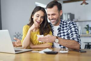 Pareja sentado a comida mesa, utilizando computadora portátil, comprobación cuentas foto