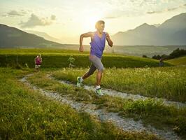 Atletas corriendo en campo camino a puesta de sol foto