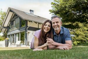 Portrait of happy couple lying in garden of their home photo