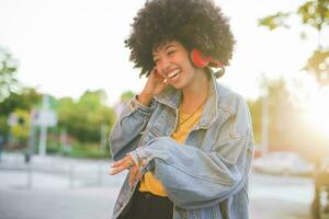 contento joven mujer con afro peinado bailando en el ciudad foto