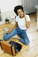 joven mujer sentado en suelo escuchando música desde grabar jugador, utilizando auriculares foto