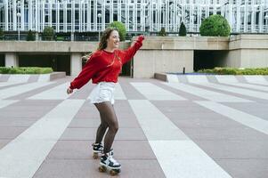 contento joven mujer rodillo Patinaje en el ciudad foto