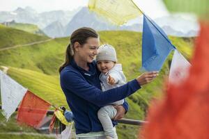 Germany, Bavaria, Oberstdorf, happy mother carrying little daughter on a mountain hut surrounded by pennants photo