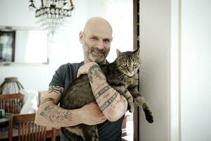 Tattooed man carrying his cat photo