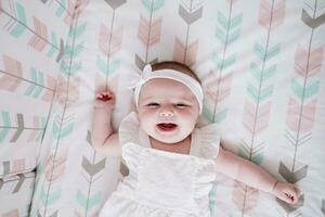Cheerful baby girl lying in crib at home photo