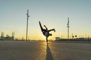 acróbata haciendo parada de manos en el ciudad a amanecer foto