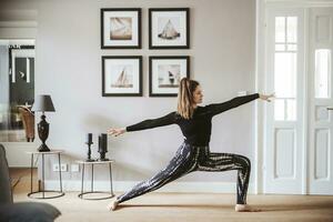 mujer practicando yoga a hogar, guerrero actitud foto