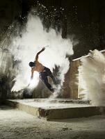 Man jumping in flour dust cloud during freerunning exercise photo