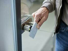 Close-up of businessman in office opening door with access card photo