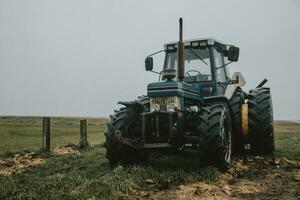 azul antiguo abandonado tractor para que lleva turistas a el mando isla, en el apuntalar de del Norte mar en Dinamarca durante el nublado otoño día foto