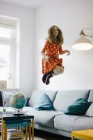 Carefree girl jumping on couch at home photo