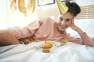 contento joven mujer con magdalena durante cumpleaños foto