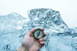 Iceland, Hand of man holding navigational compass in front of large block of ice photo