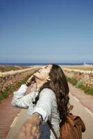 Cheerful young brunette woman holding hand of man photo