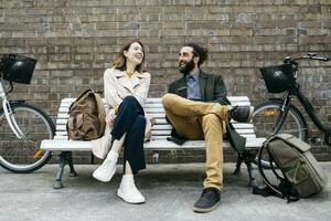 Happy couple sitting on a bench next to e-bikes talking photo
