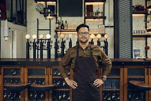 Portrait of a confident waiter at the counter in a pub photo