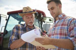Two farmers discussing data from clipboard on the farm photo