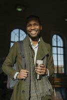 retrato de contento elegante hombre con reutilizable taza en el tren estación foto