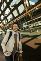 Portrait of laughing man with backpack and E-Scooter in the city photo