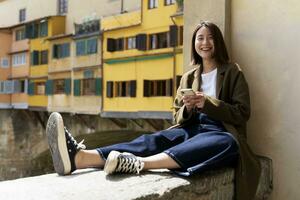 Italy, Florence, happy young woman resting on a wall in the city photo