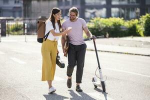 joven Pareja con eléctrico scooter y teléfono inteligente caminando en el calle foto