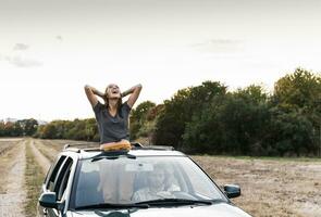 despreocupado joven mujer mirando fuera de techo corredizo de un coche foto