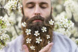 retrato de hipster con blanco árbol flores en su barba foto