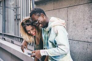 Laughing couple using cell phone outdoors photo