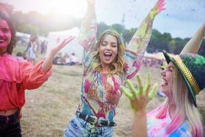 Friends dancing during music festival, colour powder photo