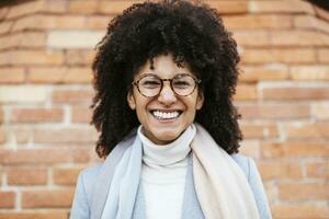 Portrait of happy woman at brick wall photo