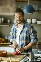 Young man preparing food at home, slicing vegetables photo