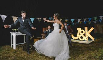 Happy bride and man dancing on a night field party photo