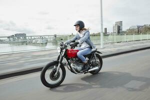 Germany, Cologne, young woman riding motorcycle on bridge photo