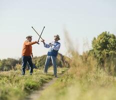 Two old friends fencing in the fields with their walking sticks photo