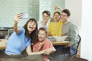 madre y su cuatro hijos tomando teléfono inteligente selfies a almuerzo foto